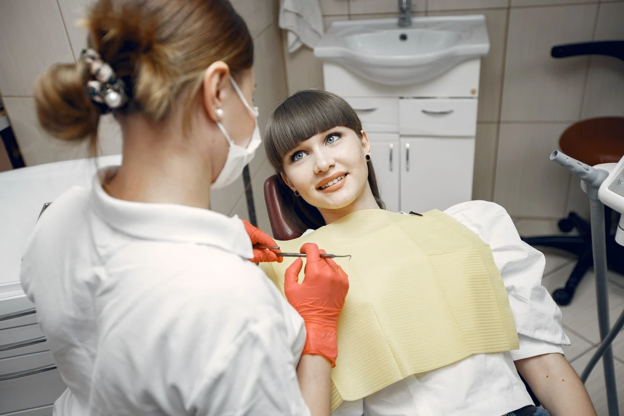 A dentist wearing a mask examines a patient in a contemporary dental office setting