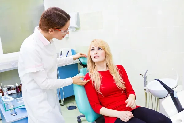 A woman in a dental chair receiving a checkup and professional consultation for a toothache.