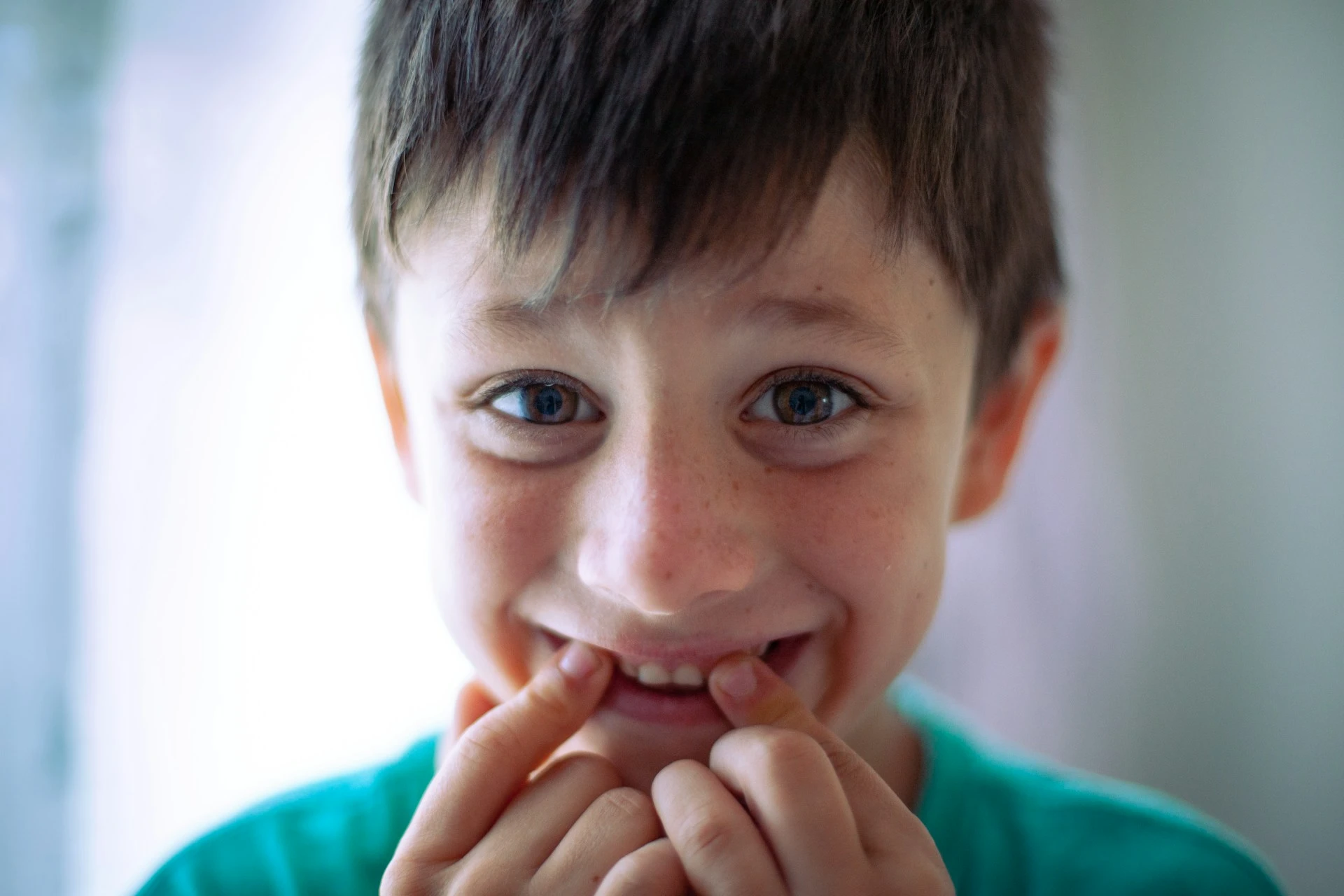 A young boy with fingers on his teeth