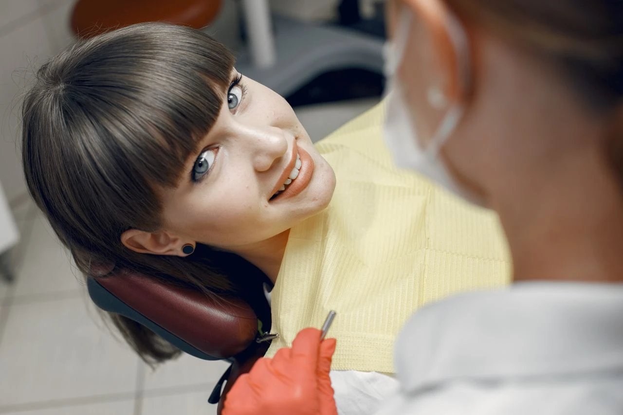 A young woman smiles while seated in a dentist chair during a dental check-up