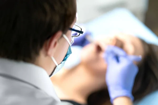 Close-up of a dental specialist performing an operation or caries treatment.