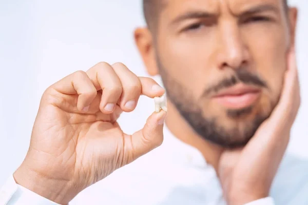 Close-up of a patient holding an extracted wisdom tooth following oral surgery