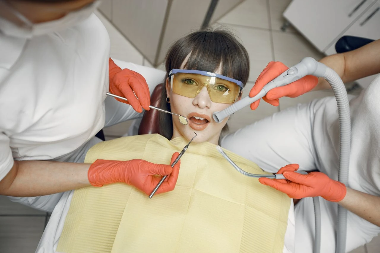 Dentist performing a checkup with protective gear and tools in a clinic