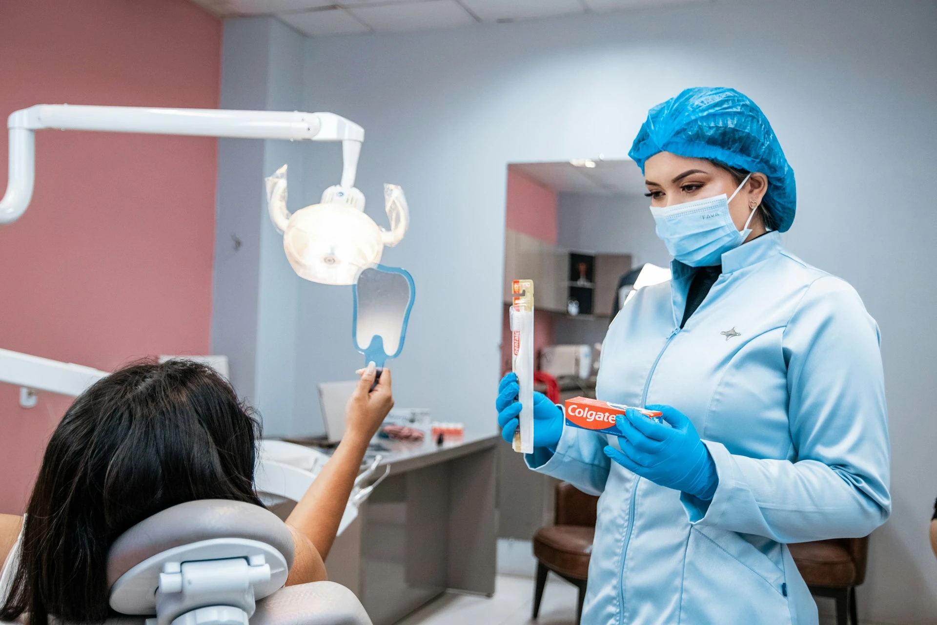 Dentist showing brush and tooth paste to a patient sitting in a dental chair