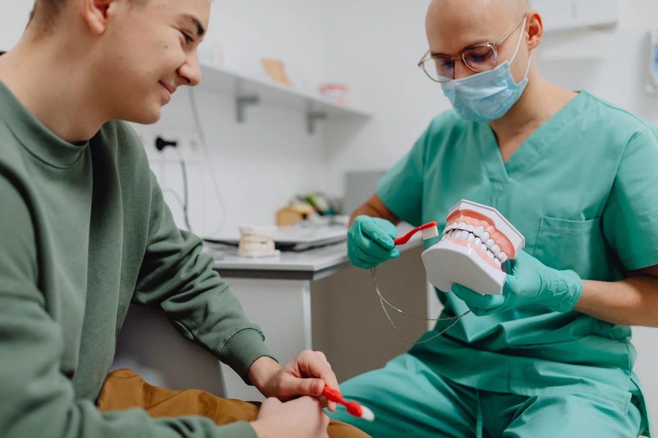 Dentist using a dental model to showcasing a teenager learn brushing techniques