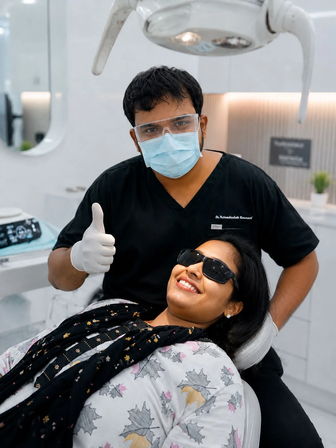 Dr. Rahmath giving a thumbs-up next to a smiling patient resting comfortably in a dental chair.