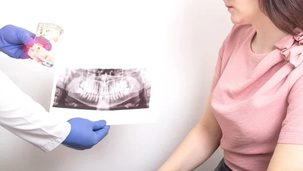 Reviewing a dental panoramic X-ray film and clear teeth model during an oral surgery or wisdom tooth evaluation