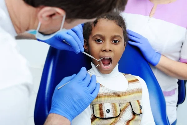 The dentist examines the mouth and teeth of a young child